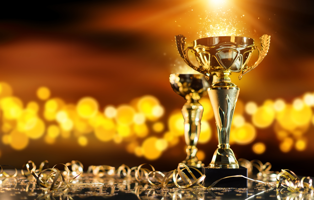 Champion,Golden,Trophy,On,Wood,Table,With,Blur,Spot,Lights