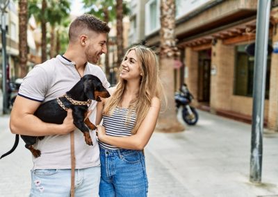 Young,Caucasian,Couple,Hugging,And,Smiling,Happy,Standing,With,Dog