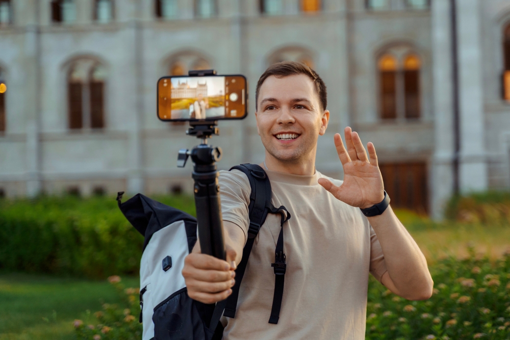Happy,Male,Travel,Blogger,Vlogging,With,Smartphone,And,Waving,To