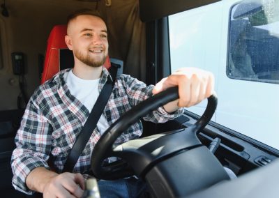 Young,Male,Truck,Driver,Smiling,,Wearing,A,Seatbelt,And,Holding