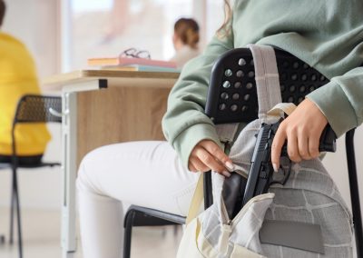 Teenage,Girl,Taking,Gun,From,Backpack,In,Classroom,,Closeup.,School