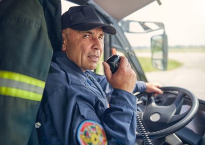 Waist,Up,Portrait,Of,Happy,Young,Fireman,Driving,Firetruck,While
