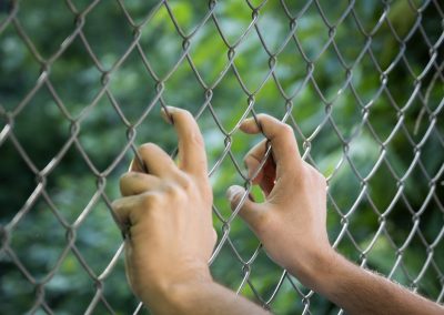 FEMA Just Sent Florida $58 Million and Every Critic of Alligator Alcatraz Owes Ron DeSantis an Apology Hands,Holding,Onto,A,Chain,Link,Fence,,Representing,Confinement,,Societal