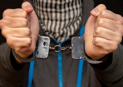A,Man,In,Handcuffs,Hiding,His,Face,With,A,Handkerchief