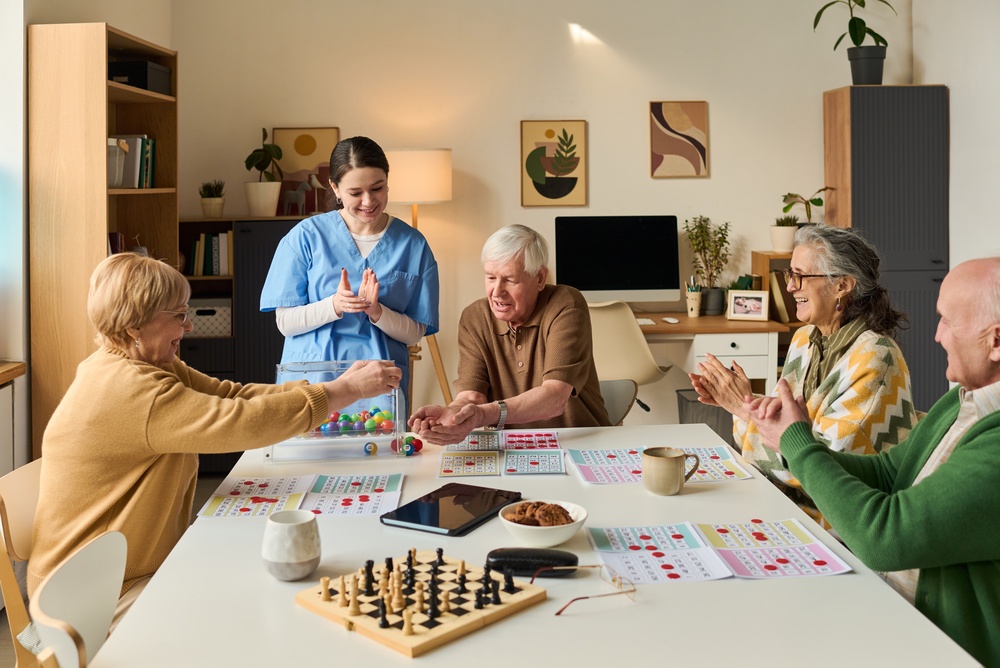Senior,Group,Playing,Bingo,With,Female,Caregiver,,Interacting,Around,Activity