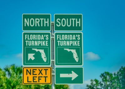 Florida’s,Turnpike,Road,Signage,Against,Palms,And,Blue,Sky.