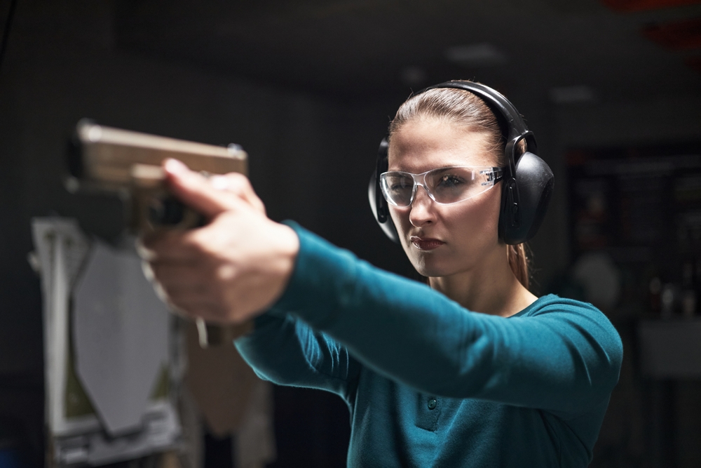 Caucasian,Young,Adult,Woman,Wearing,Protective,Glasses,And,Earmuffs,Aiming